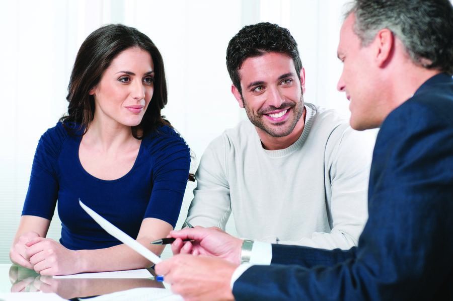Couple consulting with an advisor about a home automation, lighting, or shading project while reviewing paperwork