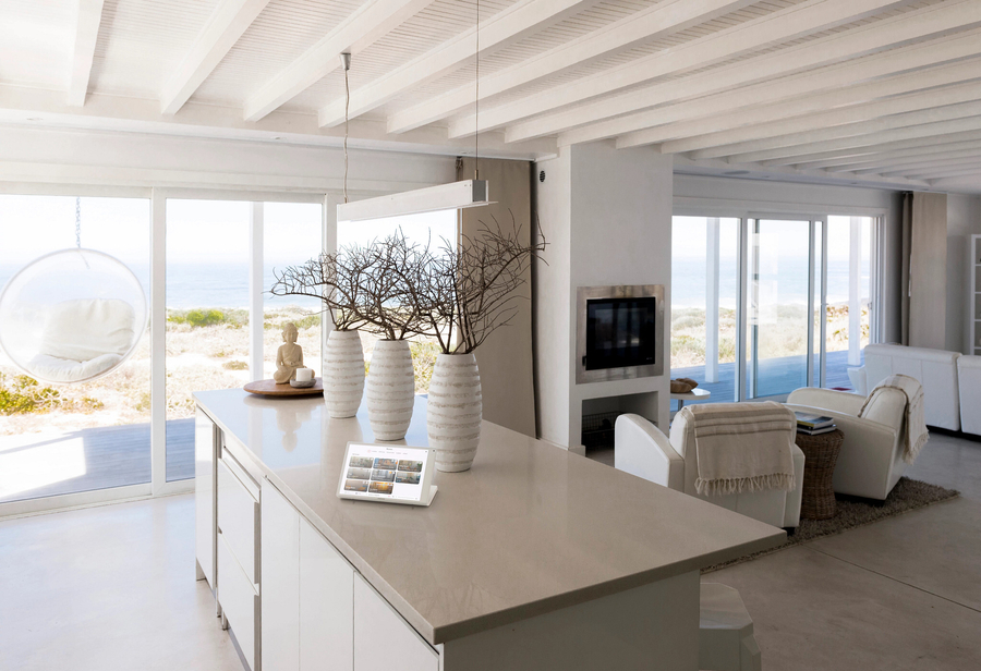 Coastal home interior with a Crestron control tablet on the counter and motorized shades opened on the windows.