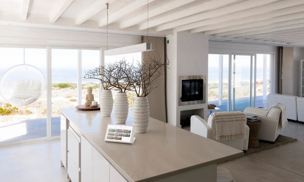 Coastal home interior with a Crestron control tablet on the counter and motorized shades opened on the windows.